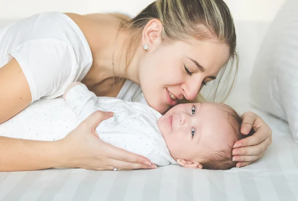 Primo piano ritratto di madre felice baciare il suo bambino sul letto — Foto Stock