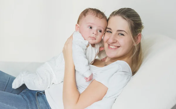 Retrato tonificado de madre alegre acostada con su bebé en la cama —  Fotos de Stock