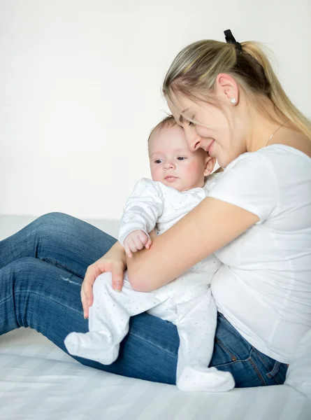 Porträtt av glada mor gunga hennes 3 månader gammal baby i sängen — Stockfoto