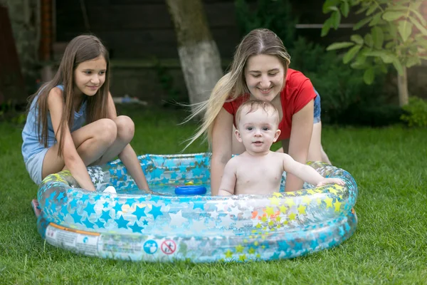 Mladá matka a starší sestra hraje s chlapeček v plavání — Stock fotografie