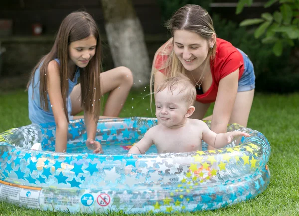 Bebê bonito nadando na piscina exterior com mãe e irmã mais velha — Fotografia de Stock