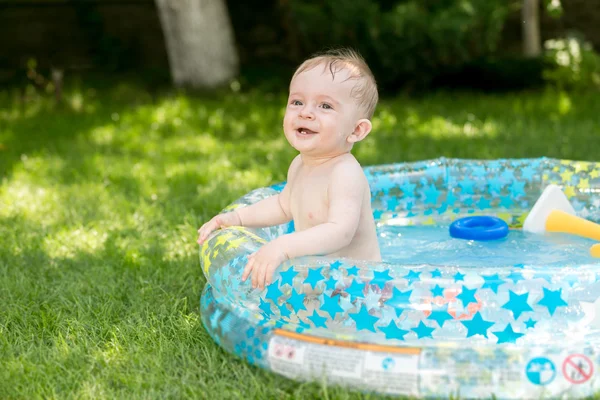 Sorrindo menino bonito se divertindo na piscina no jardim — Fotografia de Stock