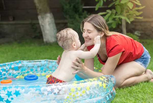 Giovane madre che gioca con il suo bambino in piscina gonfiabile po — Foto Stock