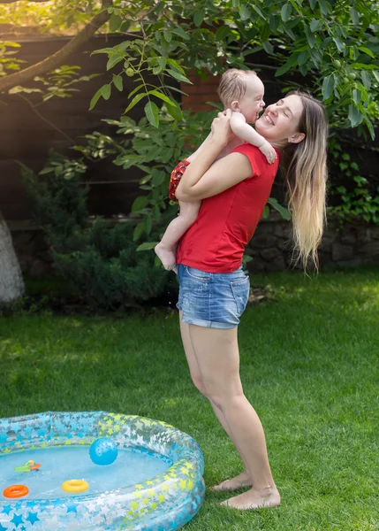 Mère joyeuse embrassant son bébé garçon après avoir nagé dans la piscine — Photo