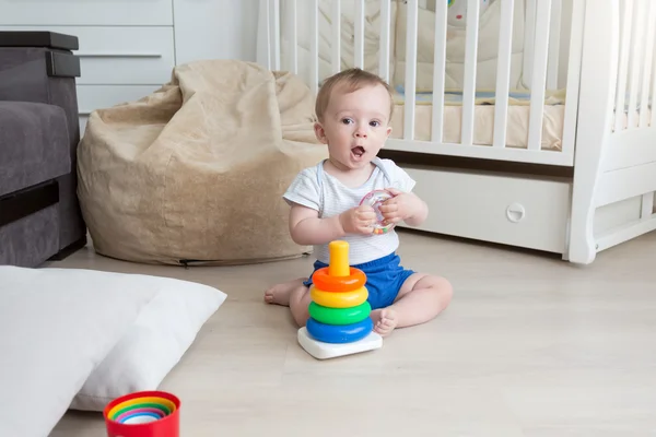 9 meses de idade bebê jogando no chão e montagem de torre de brinquedo — Fotografia de Stock