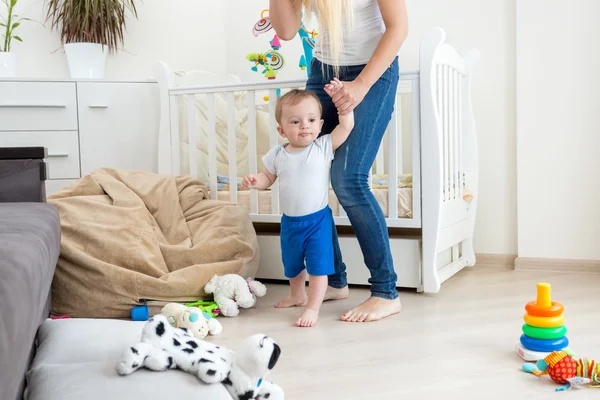 Mãe segurando menino pelas mãos e andando na sala de estar — Fotografia de Stock