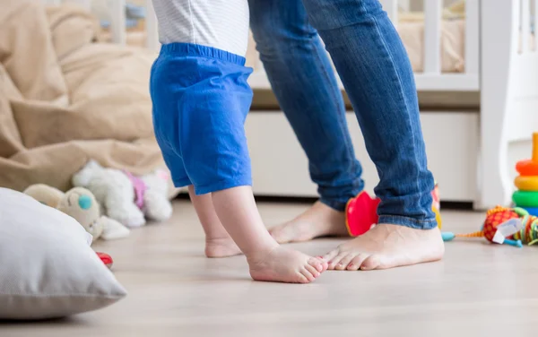 Närbild av bedårande baby's och mors fötter på golvet på living — Stockfoto