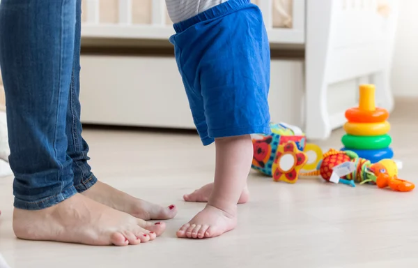Gros plan des pieds du petit bébé sur le sol du salon à côté de mot — Photo