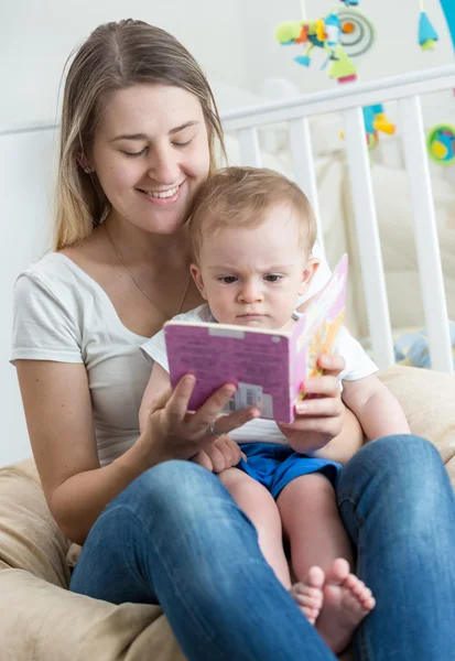 Mooie lachende moeder lezing verhaal aan haar 9 maanden oude baby — Stockfoto