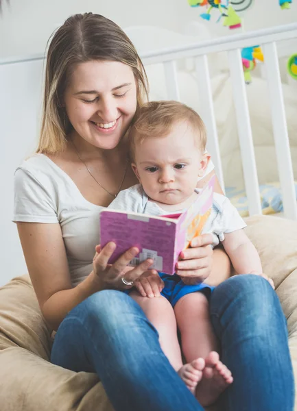 Porträtt av pojke sitter i mödrar knä och läsa bok — Stockfoto