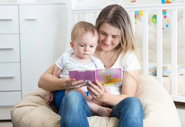 Portrét krásné matka dítěte hospodářství na její klín a čtení — Stock fotografie