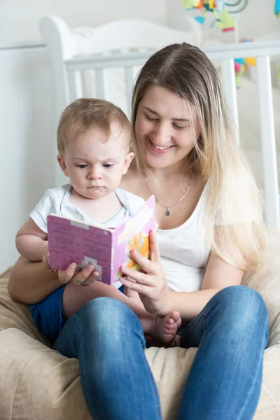 Belle mère souriante assise dans un sac à haricots et un livre de lecture pour — Photo