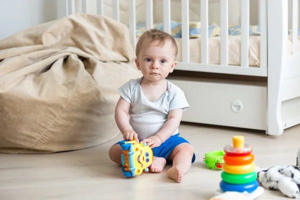 Menino brincando no chão com carro de brinquedo colorido — Fotografia de Stock