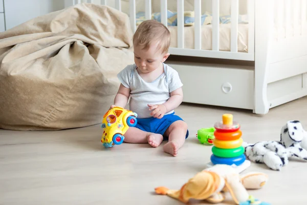 Alegre 10 meses de idade bebê jogando no chão com carro de brinquedo e co — Fotografia de Stock