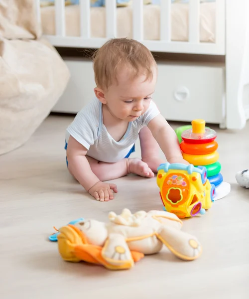9 місяців хлопчик грає з барвистими іграшками на підлозі наживо — стокове фото