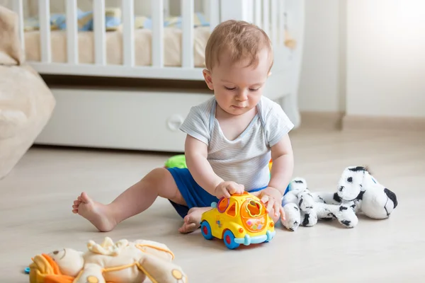 Adorable baby boy playing with toy car on floor at living room — Stock Photo, Image