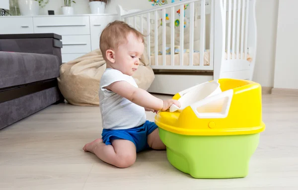 Förtjusande baby sitter på golvet och tittar på potta — Stockfoto