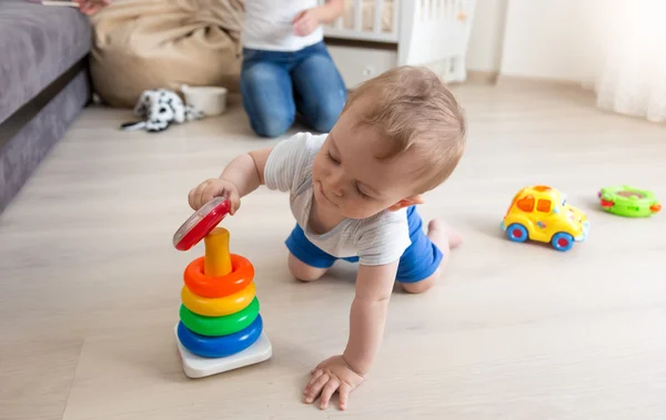Adorabile bambino strisciando sul pavimento e assemblando colorato giocattolo rimorchio — Foto Stock