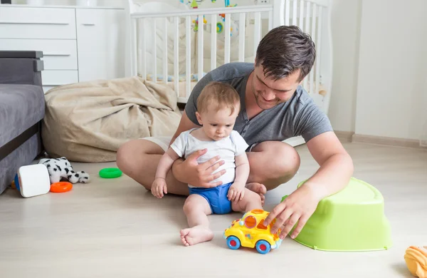 Joven padre y su niño jugando con coche de juguete en el suelo en casa — Foto de Stock