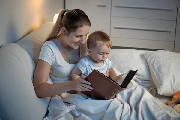 Primer plano de la hermosa madre sonriente contando la historia a su bebé en —  Fotos de Stock