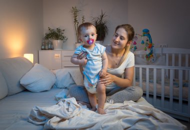 Annem geceleri yatakta onun bebek çocuk için dağınık çocuk bezi değiştirme