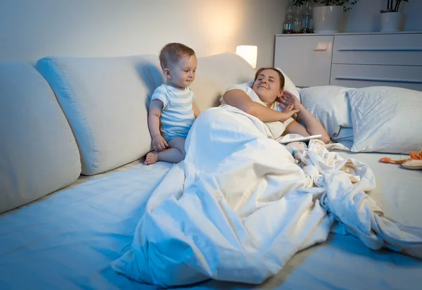 Bebé sin dormir despertando a la madre durmiendo en la cama —  Fotos de Stock