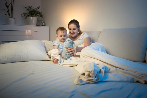 Madre jugando con su bebé por la noche con la muñeca —  Fotos de Stock