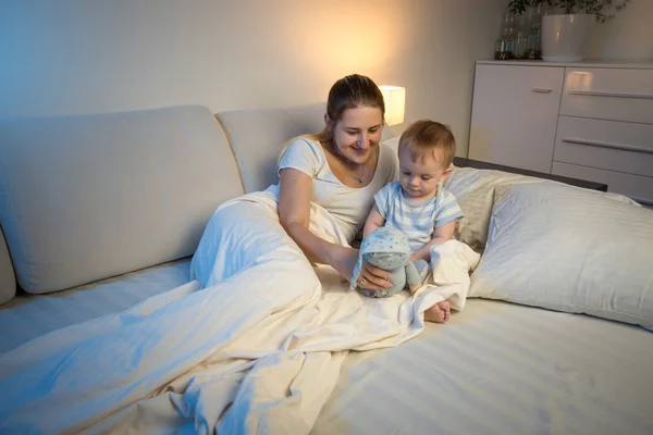 Очаровательный ребенок играет на кровати поздно ночью со своей матерью — стоковое фото