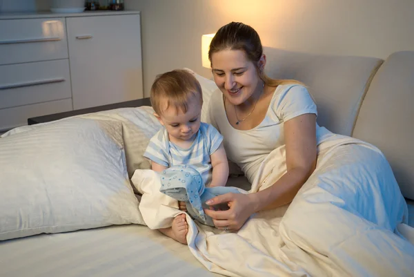 Bebê brincando com boneca na cama com a mãe — Fotografia de Stock