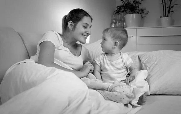 Retrato en blanco y negro de la madre hablando con su bebé en la cama — Foto de Stock