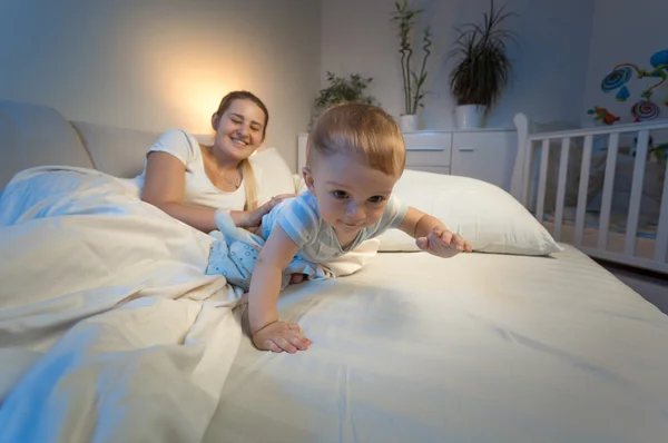 Porträt eines entzückenden Jungen, der nachts auf dem Bett kriecht — Stockfoto