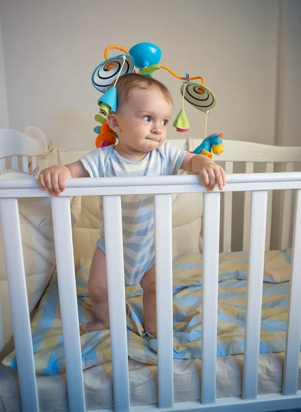 Portrait of baby boy standing in crib at night — Stock Photo, Image