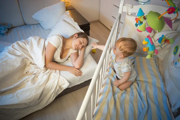 Crying baby waking up and reaching his mother at night — Stock Photo, Image