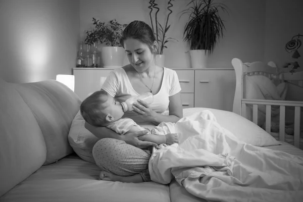 Svartvita porträtt av mamma matar sitt barn på natten fro — Stockfoto