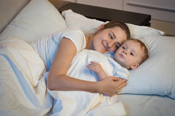 Mutlu gülümseyen anne bebeğini ni yatakta kucaklayan portresi — Stok fotoğraf