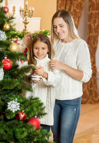 Porträt eines Mädchens, das der schönen jungen Mutter beim Dekorieren hilft — Stockfoto