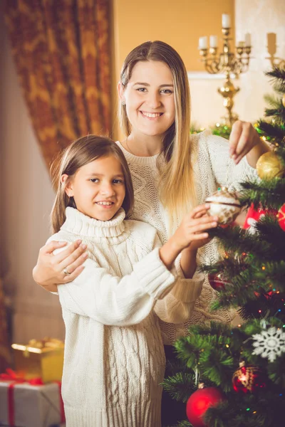 Tonad porträtt av leende flicka att hjälpa mor dekorera julstämning — Stockfoto