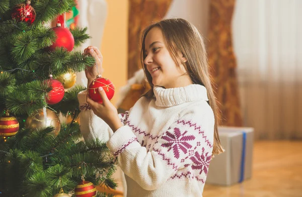 Tónovaný portrétu roztomilé dívky v svetru, zdobení vánočního stromu — Stock fotografie