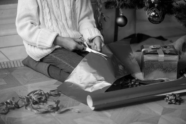 Schwarz-Weiß-Bild des niedlichen Mädchens, das Geschenkpapier schneidet unter — Stockfoto