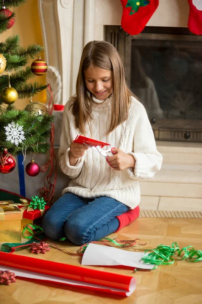 Chica adolescente haciendo copos de nieve de papel en la sala de estar en decorado — Foto de Stock