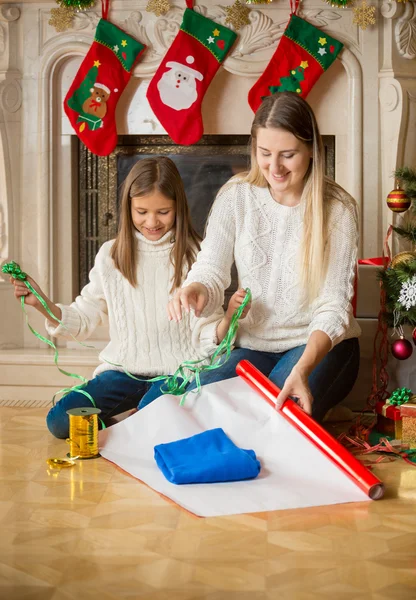 Šťastná Dcera a matka balí svetr do balicího papíru na — Stock fotografie
