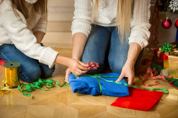 Closeup image of woman and girl wrapping sweater in decorative p — Stock Photo, Image