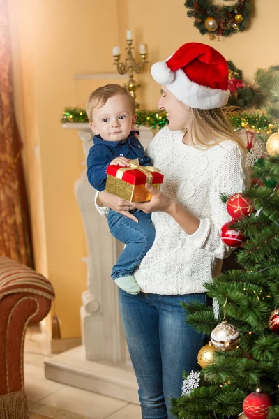 Porträt einer glücklichen Mutter, die ihrem kleinen Sohn auf Chris ein Geschenk macht — Stockfoto