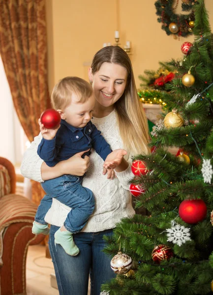 笑顔の母親と赤ちゃん男の子飾るクリスマス ツリー baubl — ストック写真