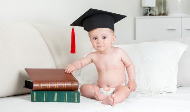 10 aylık bebek kitap yığını ile oturan kolej şapkalı