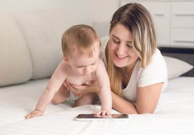 Gülümseyen anne bebekle oynarken tonda portresi tablet com