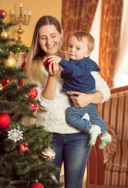 Šťastná mladá žena se svým synem miminko zdobení vánočního stromu — Stock fotografie