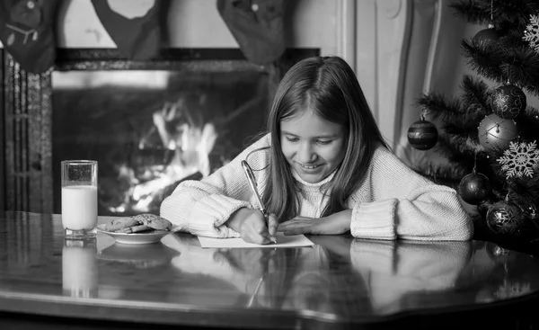 Retrato preto e branco da menina escrevendo carta para o Papai Noel em livi — Fotografia de Stock