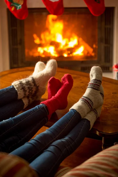 Three pair of feet in socks warming at burning fireplace at hous — Stock Photo, Image