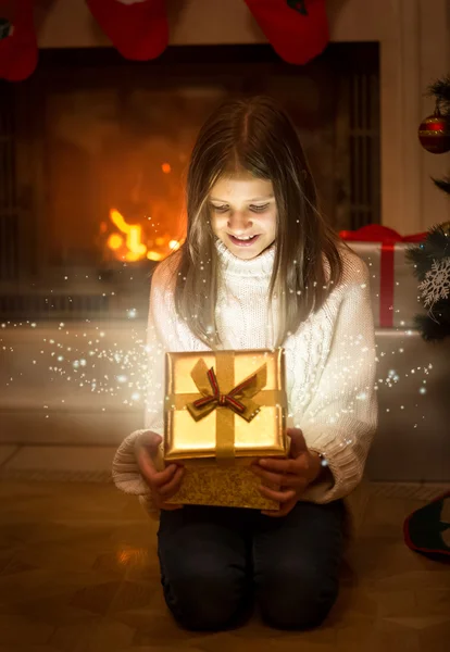 Menina sorridente feliz abrindo brilhante caixa de presente de Natal. Luz e s — Fotografia de Stock